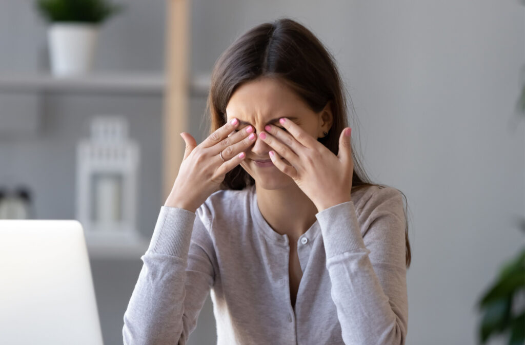 A woman rubbing her eyes due to irritation felt as a result of dry eye.
