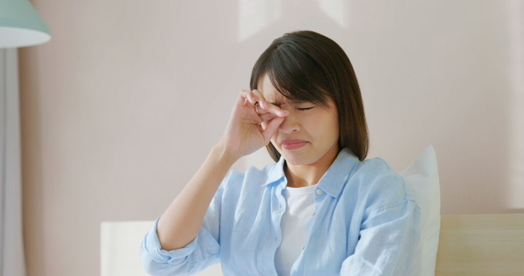 A young woman rubbing her eyes as she experiences discomfort due to dry eye.