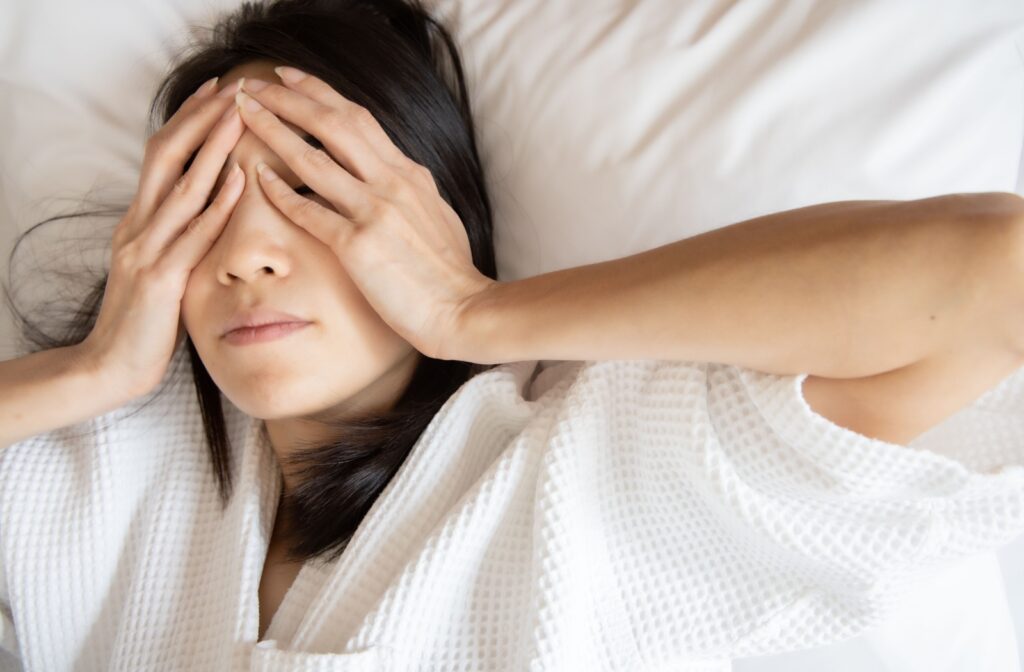 A woman waking up in the morning rubbing her dry irritated eyes.